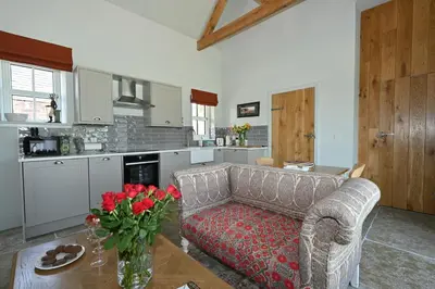 a living room with a couch and a table with roses at Milton Farm in Buchanty