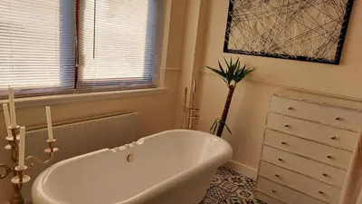 a white bath tub in a bathroom with a dresser at Luxurious room with a private bathtub and shared toilet and kitchen 10mins from City Centre in Bailleston