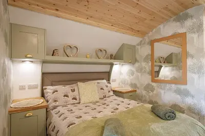 a bedroom with a bed and a mirror on the wall at The Galloway Steading -The Hedgehog's Hideout family cabin with Hot Tub and Fire Pit in Glenluce