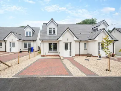 a large white house with a driveway at Riverbank in Lamlash