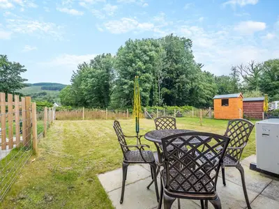 a patio with a table and chairs and a backyard at Riverbank in Lamlash