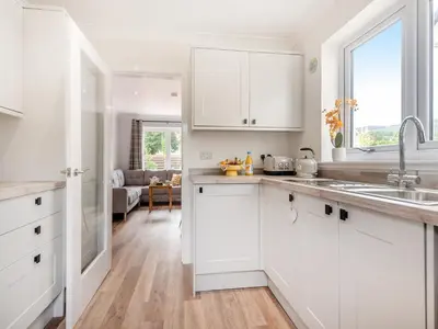 a white kitchen with white cabinets and a sink at Riverbank in Lamlash