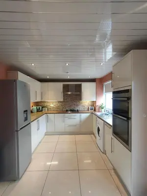 a large kitchen with white cabinets and stainless steel appliances at Troon Beach and Golf House in Barassie
