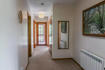 a hallway with white walls and a mirror on the wall at Heatheryhaugh Lodges in Moffat