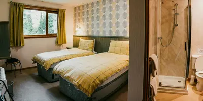 two beds in a bathroom with a shower at Heatheryhaugh Lodges in Moffat