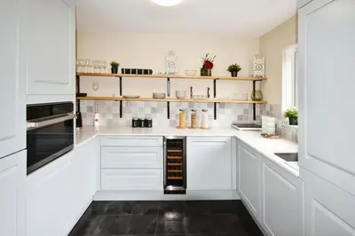 a white kitchen with white cabinets and shelves at Beautiful house in Clydebank in Glasgow