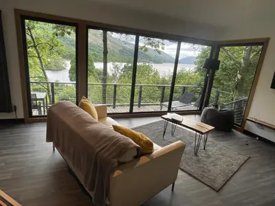 a living room with a couch and a large window at Cherrybrae Cottage in Saint Fillans