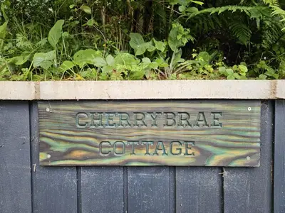 a sign on the side of a fence at Cherrybrae Cottage in Saint Fillans