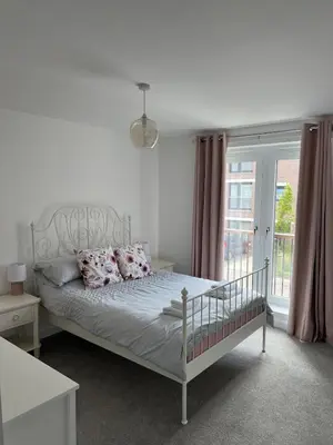 a bedroom with a white bed with pillows and a window at Dunmore Rooftop in Glasgow