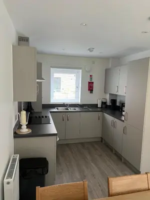 a kitchen with white cabinets and a window at Dunmore Rooftop in Glasgow