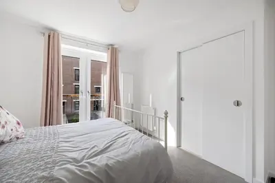 a white bedroom with a bed and a large window at Dunmore Rooftop in Glasgow