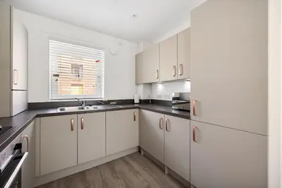a white kitchen with white cabinets and a window at Dunmore Rooftop in Glasgow