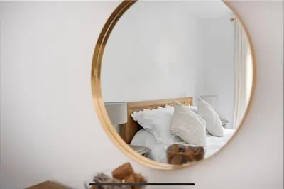 a mirror reflecting a bed with white pillows at Dunmore Rooftop in Glasgow