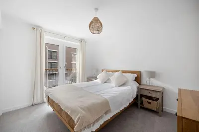 a white bedroom with a bed and a window at Dunmore Rooftop in Glasgow
