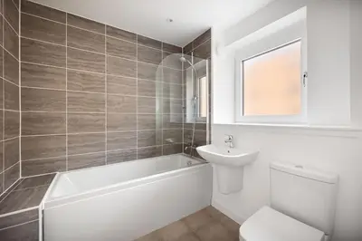 a bathroom with a tub and a toilet and a sink at Dunmore Rooftop in Glasgow