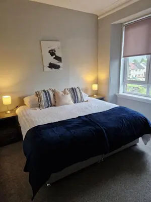 a bedroom with a large bed with a blue blanket at Star Apartment in Dumbarton