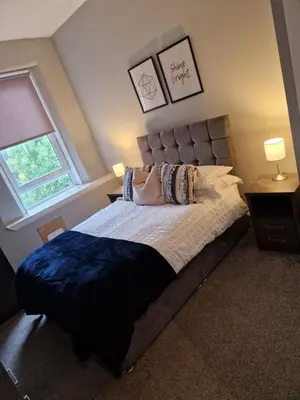 a bedroom with a large bed with a blue blanket at Star Apartment in Dumbarton