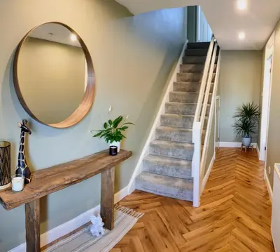 a staircase with a round mirror and a wooden floor at Troon Golf and Beach House in Troon