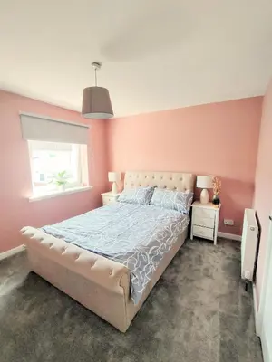 a bedroom with a large bed with pink walls at Troon Golf and Beach House in Troon