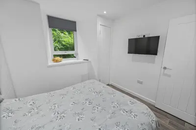 a white bedroom with a bed and a television at Cosy & Comfortable 2BR in Oban - Walk to Waterfront in Oban