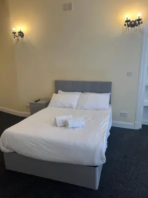 a bedroom with a white bed with two towels on it at Glasgow South 2 Bedroom Apartment in Glasgow