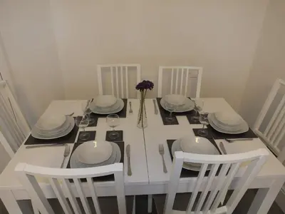 a white table with chairs and plates and a vase of flowers at Lochrin Apartments by Edinburgh City Apartments in Edinburgh