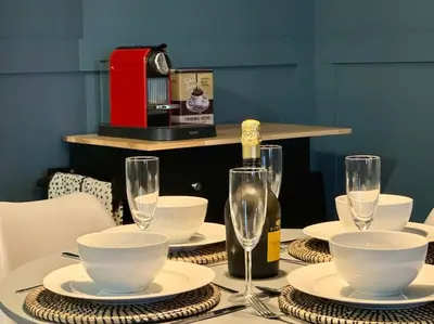 a table with plates and glasses and a bottle of wine at Stylish House with hot tub in Dalry