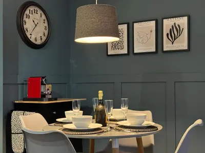 a dining room table with chairs and a clock on the wall at Stylish House with hot tub in Dalry