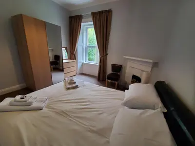 a bedroom with a large white bed with a window at Little Bay View in Oban