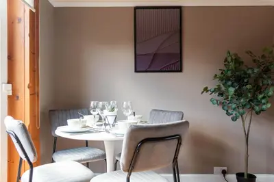 a table with chairs and a white table with wine glasses at Beth House in Bathgate