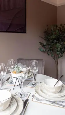 a table with white plates and wine glasses on it at Beth House in Bathgate