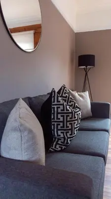 a living room with a blue couch with a mirror at Beth House in Bathgate