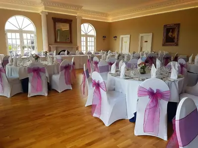 a room with white tables and chairs with pink bows at Forrester Park Resort in Dunfermline