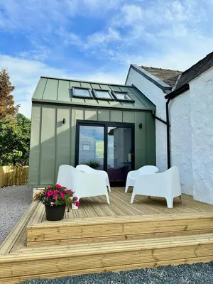 a house with two white chairs on a wooden deck at Firth View 1 - Luxury Cottage with Sea View & Hot Tub, Ayr in Ayr