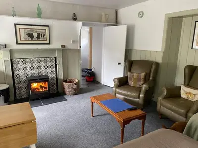 a living room with a couch and a fireplace at The Bothy at Christmas Cottage in Rowardennan