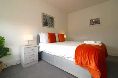 a bedroom with a bed with an orange blanket on it at Signature - Oatlands House in Glasgow