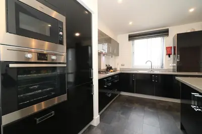 a kitchen with black cabinets and stainless steel appliances at Signature - Oatlands House in Glasgow