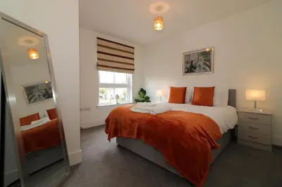 a bedroom with a bed with an orange blanket and a mirror at Signature - Oatlands House in Glasgow
