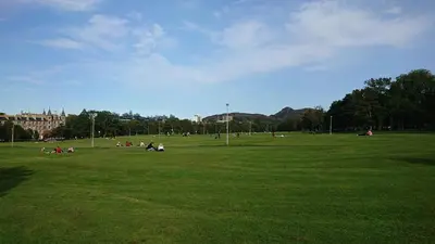 a group of people sitting in a grass field at Violet Bank Apartment Morningside in Edinburgh