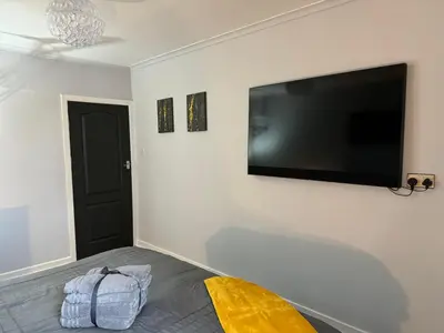 a bedroom with a large flat screen tv on the wall at The Schoolhouse Largs in Largs