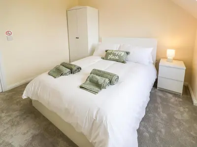 a bedroom with a white bed with three pillows on it at The Barn, Drumbow Farm in Airdrie