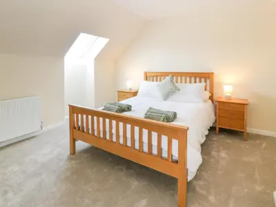a bedroom with a wooden bed and two night stands at The Barn, Drumbow Farm in Airdrie