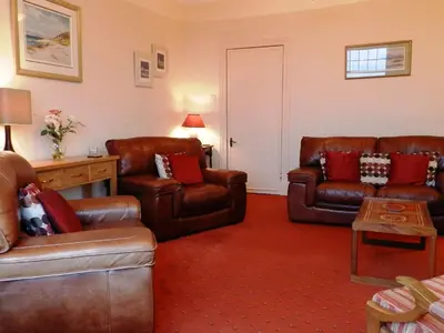 a living room with brown leather furniture in a room at Goatfell View in Brodick