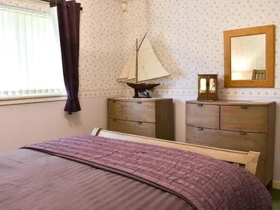 a bedroom with a bed and a dresser and a mirror at The Willows in Brodick