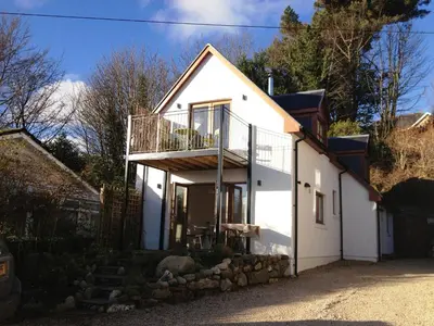 a white house with a balcony on top of it at Seaview Cottage in Lamlash