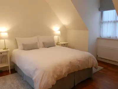 a bedroom with a large white bed with two lamps at Seaview Cottage in Lamlash