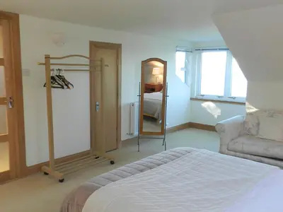 a bedroom with a bed and a chair and a mirror at Ardbeag in Whiting Bay