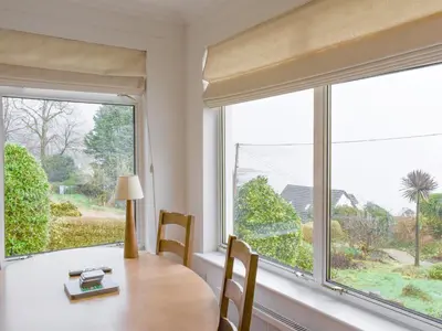 a dining room with a table and a large window at Ardbeag in Whiting Bay