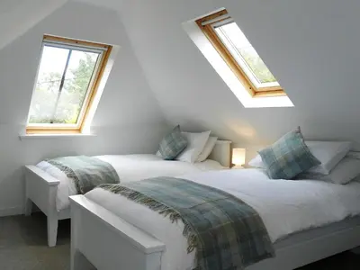two beds in a room with two windows at Craigard Cottage in Corrie