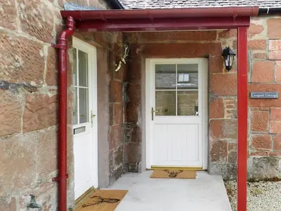 an entrance to a brick building with a white door at Craigard Cottage in Corrie